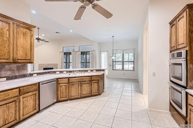 kitchen with brown cabinetry, a ceiling fan, stainless steel appliances, and a sink