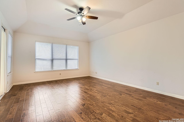 empty room featuring lofted ceiling, baseboards, a ceiling fan, and dark wood-style floors