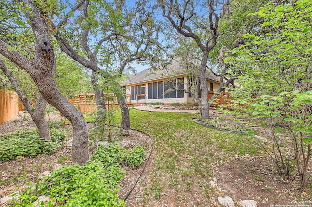 view of yard featuring fence and a sunroom