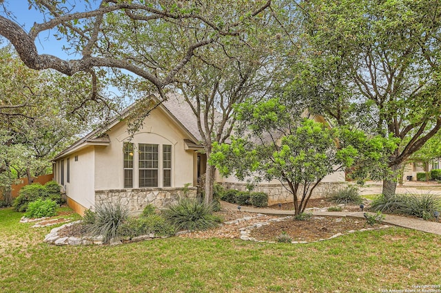 view of home's exterior featuring a yard, stone siding, and stucco siding