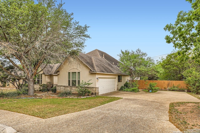 view of front facade with concrete driveway, a front lawn, fence, a garage, and stucco siding