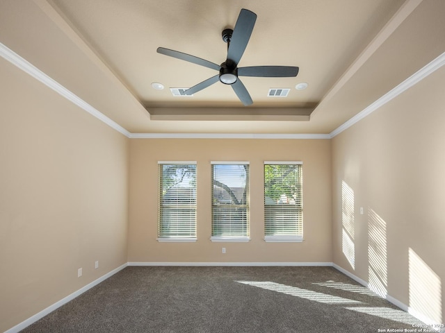 empty room with visible vents, dark carpet, and a raised ceiling