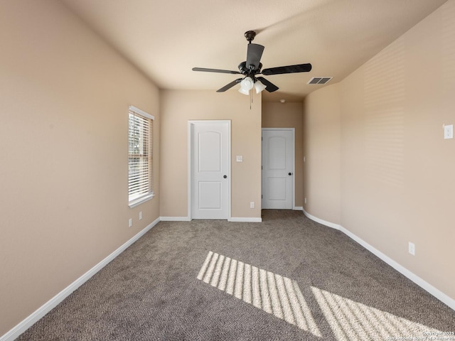 carpeted spare room with visible vents, baseboards, and ceiling fan