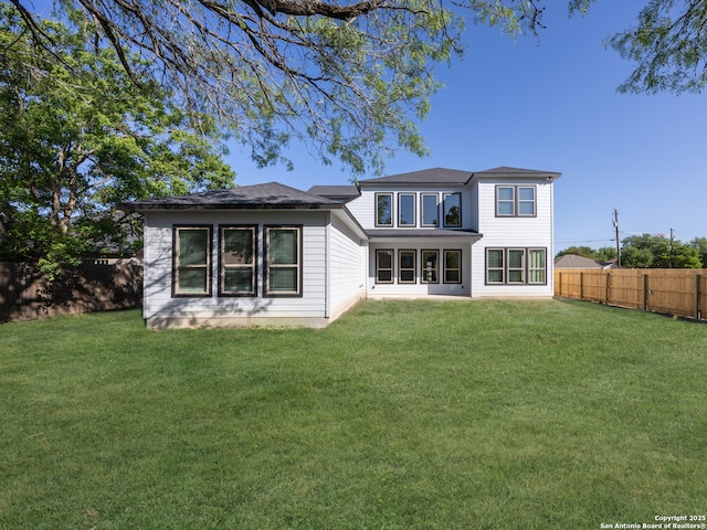 rear view of property featuring a fenced backyard and a lawn