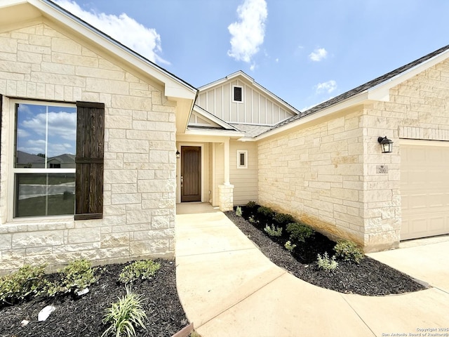 property entrance with board and batten siding, stone siding, and a garage