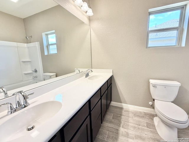 full bathroom with toilet, wood finish floors, a sink, and baseboards