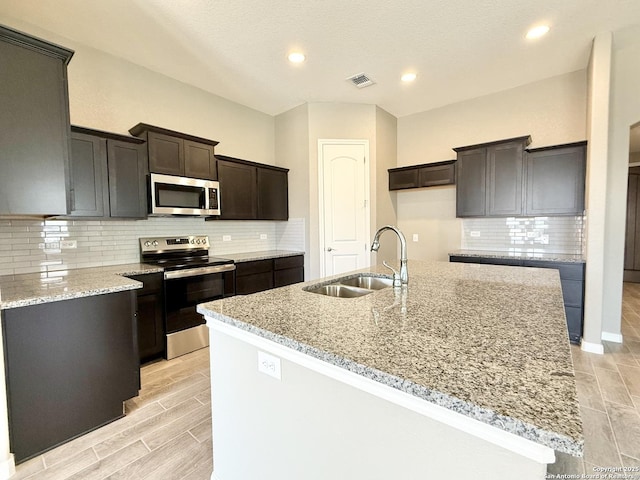 kitchen featuring light stone counters, appliances with stainless steel finishes, a sink, and visible vents