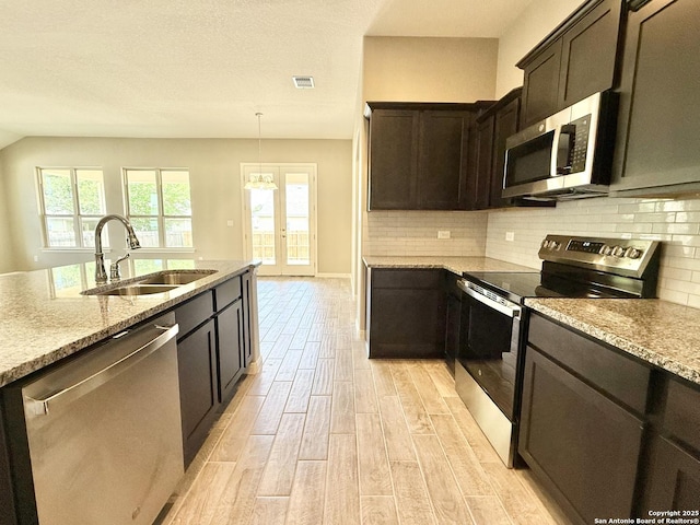 kitchen with stainless steel appliances, light wood-style flooring, a sink, visible vents, and light stone countertops