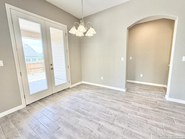 interior space with arched walkways, light wood-type flooring, baseboards, and french doors