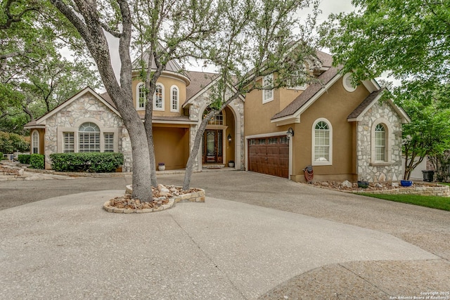 view of front of home with stucco siding, stone siding, and aphalt driveway