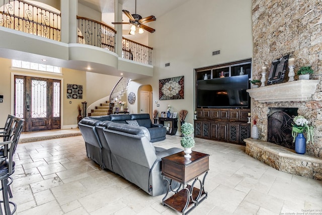 living area featuring arched walkways, stone tile flooring, visible vents, and stairs