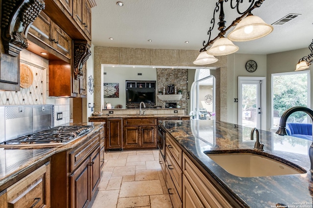 kitchen with stone tile flooring, tasteful backsplash, a sink, and visible vents