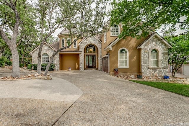 view of front of home with stucco siding, an attached garage, stone siding, and concrete driveway