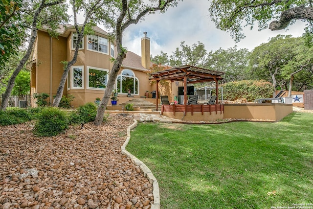 back of house featuring a chimney, fence, a pergola, stucco siding, and a lawn