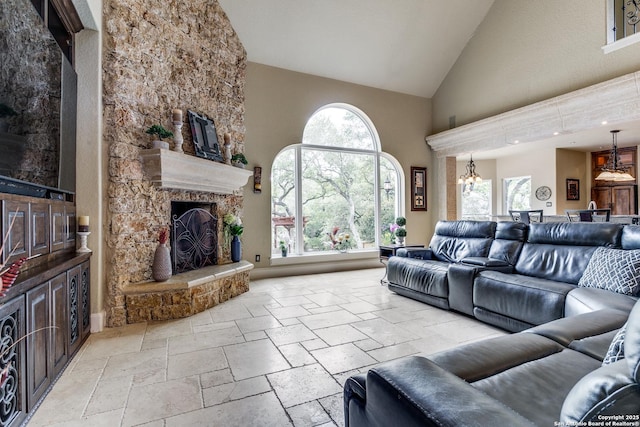 living area with stone tile floors, a fireplace, and high vaulted ceiling