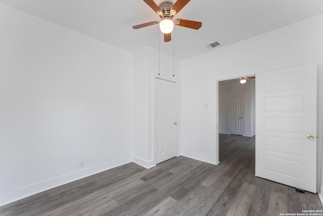 empty room featuring baseboards, visible vents, ceiling fan, and dark wood finished floors