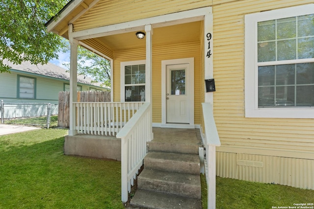 view of exterior entry with fence, crawl space, a porch, and a yard