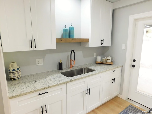 6023 Lark Valley Dr, San Antonio, TX 78242 - kitchen featuring white cabinets, a sink, light wood-type flooring, open shelves, and light stone countertops