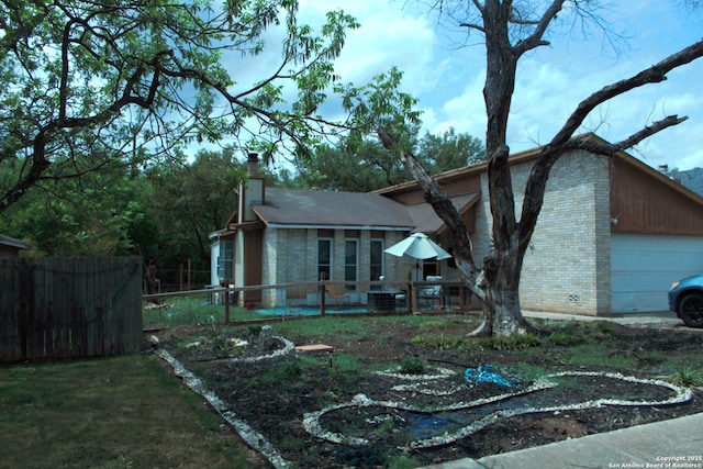 view of front facade with a chimney, brick siding, fence, and an attached garage