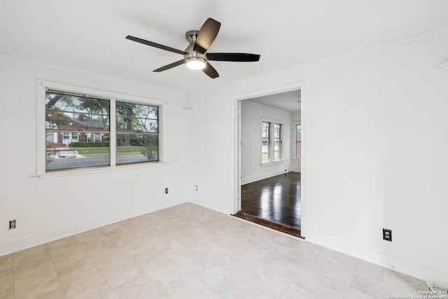 empty room featuring tile patterned floors, a ceiling fan, and baseboards