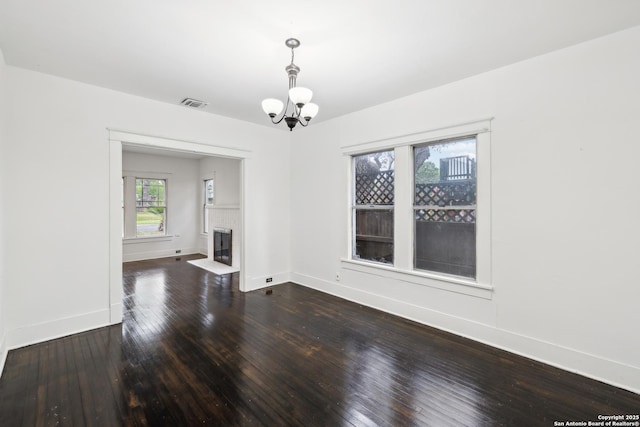 unfurnished living room with dark wood-style floors, baseboards, a chandelier, and visible vents