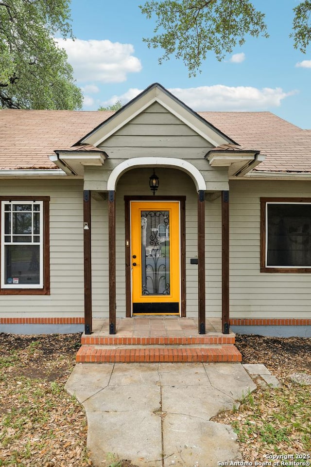 doorway to property featuring a shingled roof and covered porch