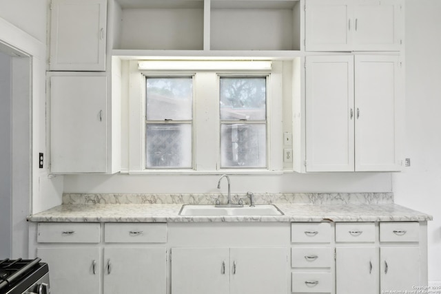 kitchen with white cabinets, light countertops, gas stove, and a sink