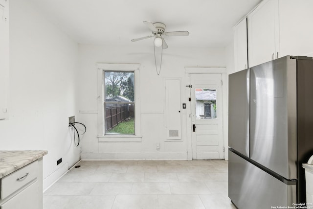 kitchen with a ceiling fan, light tile patterned floors, baseboards, white cabinetry, and freestanding refrigerator