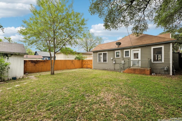 rear view of house featuring a lawn, an outdoor structure, fence, and a storage shed