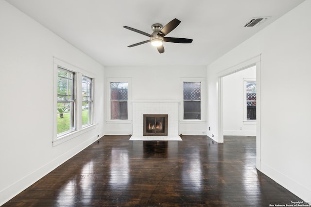 unfurnished living room with visible vents, a ceiling fan, baseboards, a brick fireplace, and dark wood-style flooring