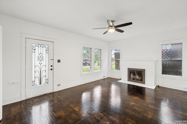 unfurnished living room featuring baseboards, a ceiling fan, a brick fireplace, and hardwood / wood-style flooring