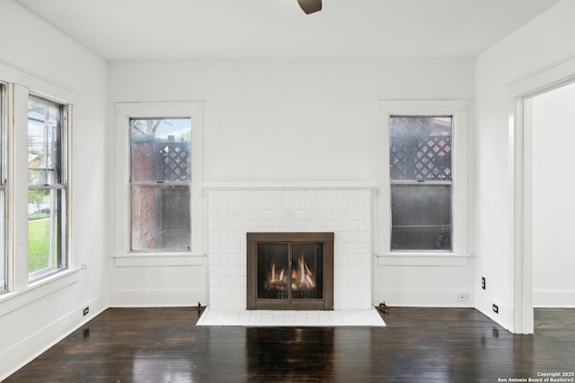 unfurnished living room featuring a tile fireplace, baseboards, a ceiling fan, and wood finished floors