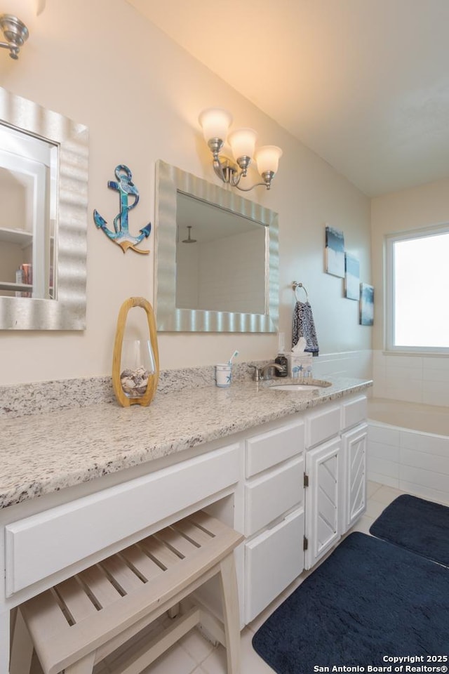full bathroom featuring vanity, tile patterned floors, and a relaxing tiled tub