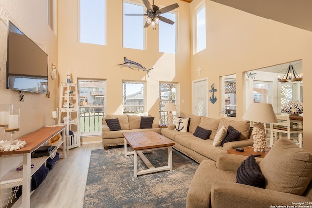living room with plenty of natural light, a towering ceiling, and ceiling fan with notable chandelier