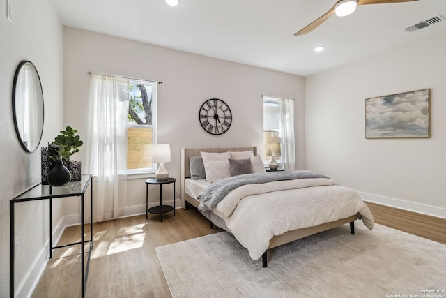 bedroom with baseboards, wood finished floors, visible vents, and recessed lighting