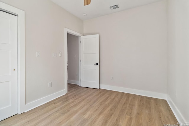 empty room featuring light wood finished floors, baseboards, ceiling fan, and visible vents