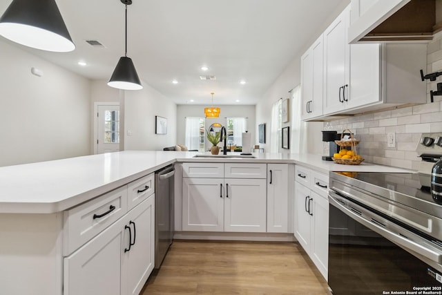 kitchen with under cabinet range hood, light countertops, visible vents, electric stove, and a sink