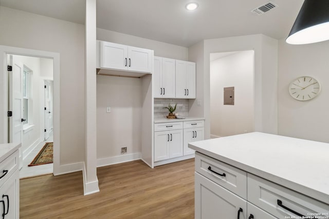 kitchen with white cabinets, light countertops, visible vents, decorative backsplash, and light wood-style flooring