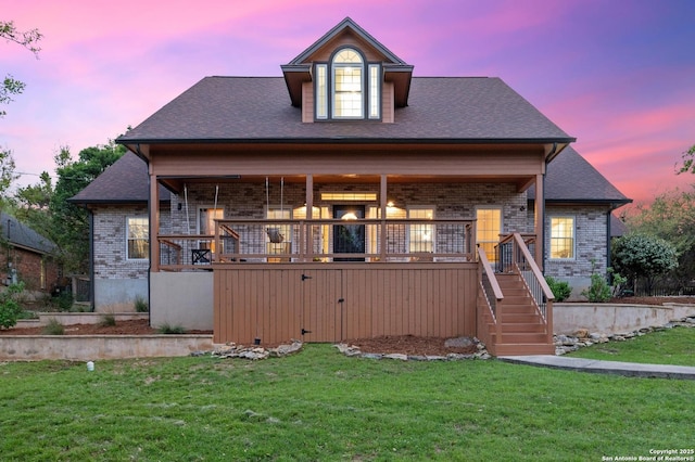 view of front of house featuring stairs, brick siding, and a front yard