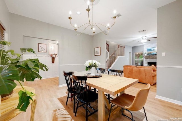 dining space featuring a fireplace, baseboards, visible vents, and light wood-type flooring