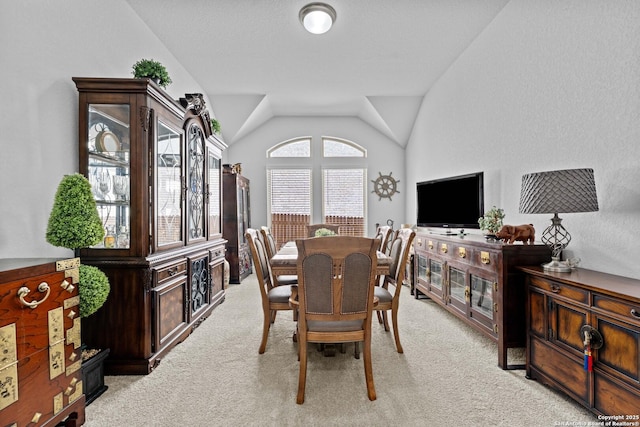 dining space featuring lofted ceiling and light colored carpet