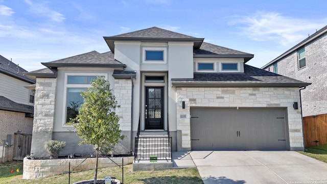 view of front of home with fence, concrete driveway, stone siding, roof with shingles, and a garage