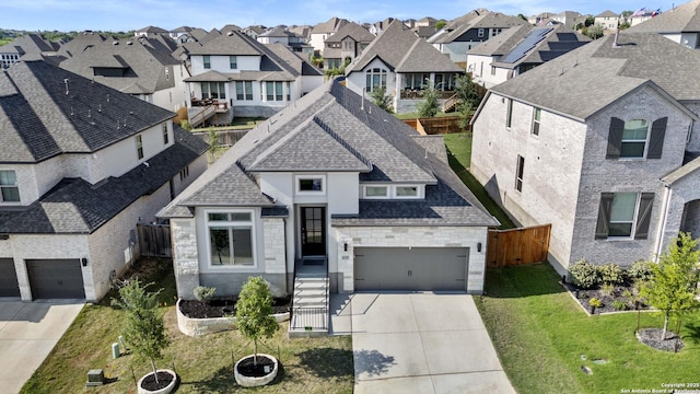 french country home featuring a residential view, driveway, stone siding, roof with shingles, and a garage