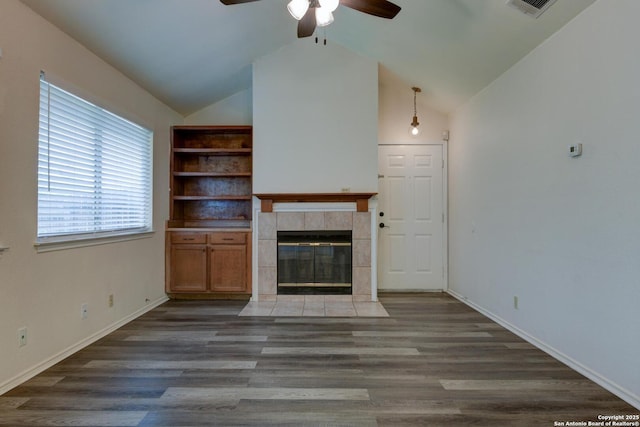 unfurnished living room featuring a ceiling fan, wood finished floors, a tiled fireplace, baseboards, and lofted ceiling