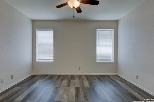 empty room featuring dark wood-type flooring, a wealth of natural light, baseboards, and ceiling fan