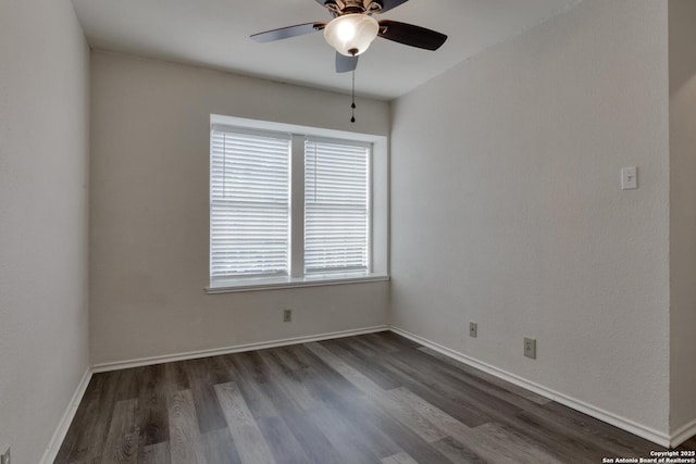 empty room with baseboards, a ceiling fan, and dark wood-type flooring