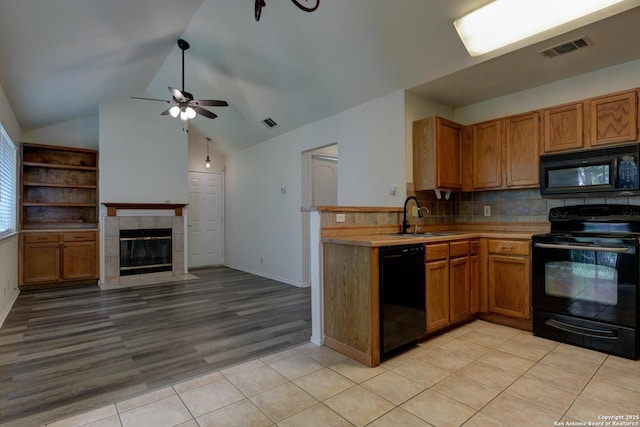 kitchen featuring vaulted ceiling, a sink, black appliances, light tile patterned floors, and visible vents
