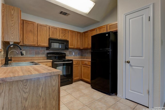 kitchen featuring a sink, light tile patterned flooring, tasteful backsplash, visible vents, and black appliances