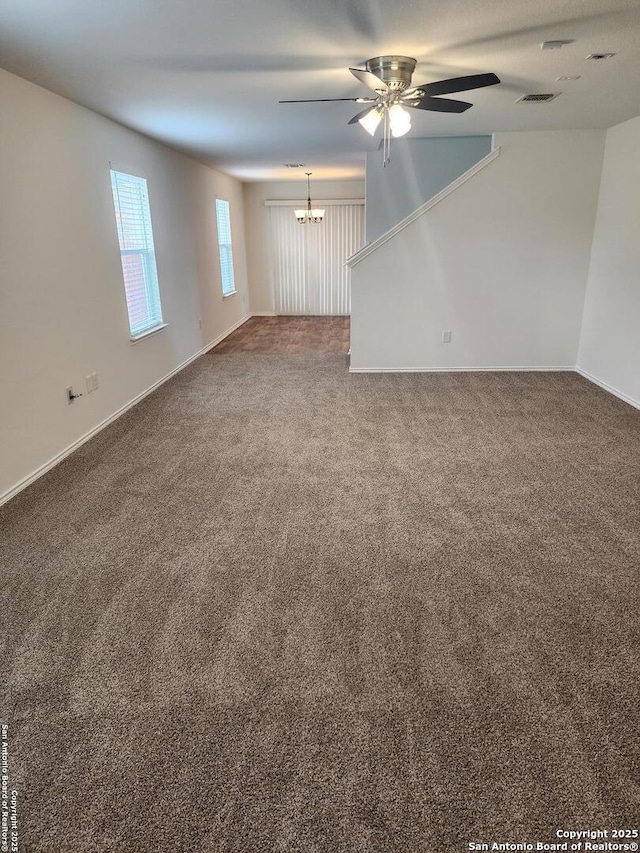 spare room featuring ceiling fan with notable chandelier, baseboards, carpet, and visible vents