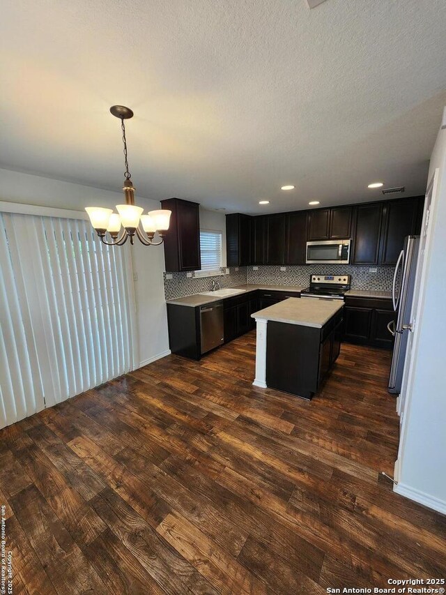 kitchen with stainless steel appliances, a center island, decorative backsplash, and dark wood-style flooring
